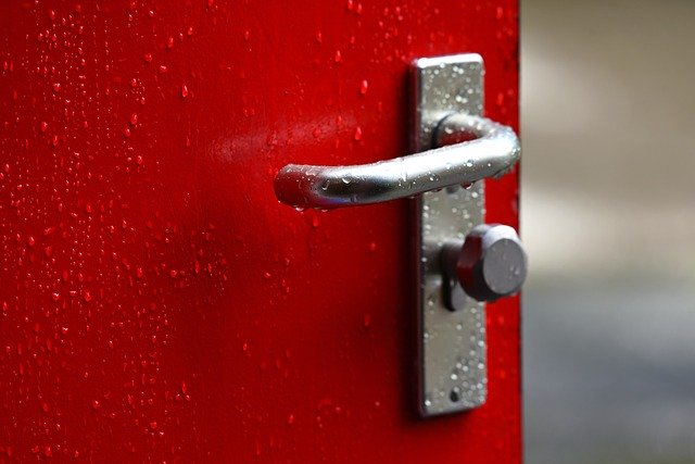 Červené pootvorené dvere so striebornou kľučkou.jpg